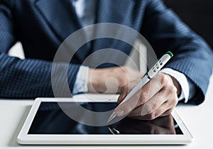 Man in business suit sitting at desk with tablet