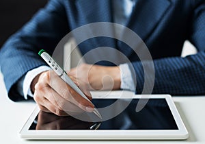 Man in business suit sitting at desk with tablet