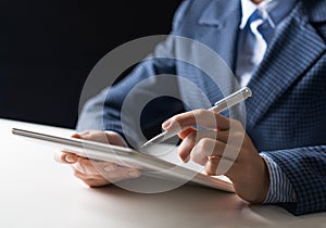 Man in business suit sitting at desk with tablet