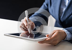 Man in business suit sitting at desk with tablet