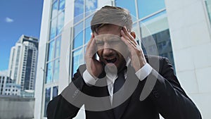 Man in business suit suffering from headache attack, magnetic storm response