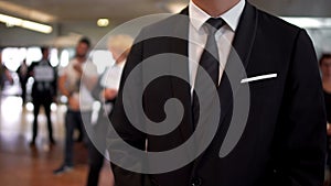 Man in business suit waiting for arrivals in airport hall, travel agent, tourism