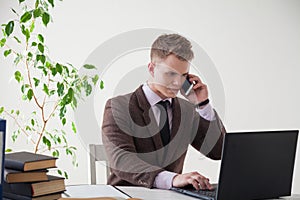 A man in a business suit works at a desk with a computer and books in the Office