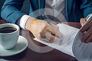 Businessman signs important legal documents on the desktop with Cup of coffee