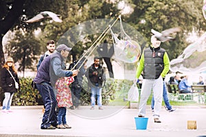 A man busker with a little girl is doing the big soap bubbles.