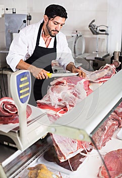 Man butcher cutting meat for client in food shop
