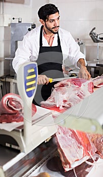 Man butcher is cutting meat on his workplace in the market.