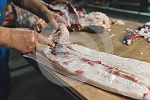 Man butcher at the freezer cutting meat. Meat pork or beef on table in butchery