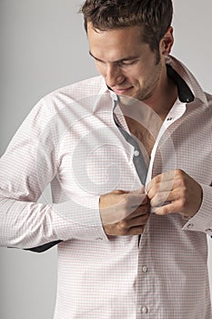 Man buttoning front of dress shirt. Men`s clothing styles businessman getting ready for work putting on clean clothes.