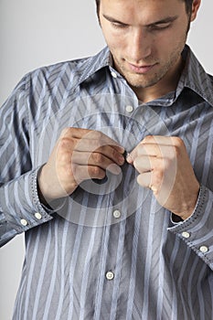 Man buttoning front of dress shirt. Men`s clothing styles getting dressed