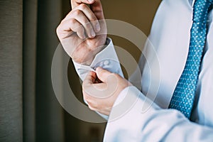 Man buttoning on the sleeve of his shirt. Zip up the cufflink