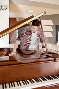 Man buyer looking on tuning keys inside grand piano under lid