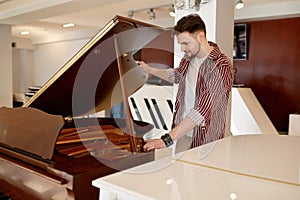 Man buyer looking on tuning keys inside grand piano under lid
