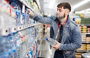 man buying still water in grocery section