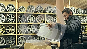 The man buys alloy wheels in his shop for his car.