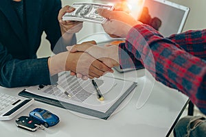 Man buys car and shakes hands with business salesman, closing car sales agreement, gesture and concept of giving keys to new owner