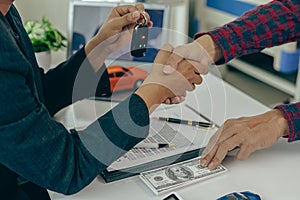 Man buys car and shakes hands with business salesman, closing car sales agreement, gesture and concept of giving keys to new owner