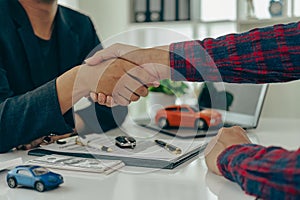 Man buys car and shakes hands with business salesman, closing car sales agreement, gesture and concept of giving keys to new owner