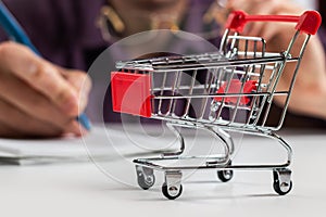 Man calculates the budget. Shopping cart a on table with calculator and paper