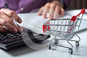 Man calculates the budget. Shopping cart a on table with calculator and paper. Budget of poor and low income family