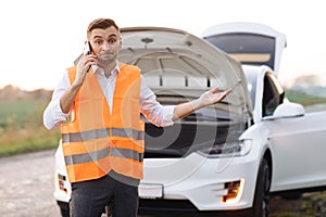 Man calling car assistance services because his electric car is broken. Concept road accident. Help repair. Man in a
