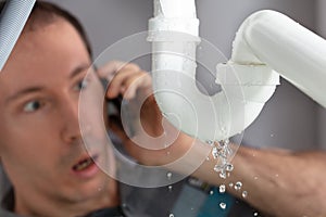 Man Calling Plumber To Fix Sink Pipe Leakage