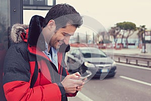 Man calling a taxi with a smartphone app standing along the road