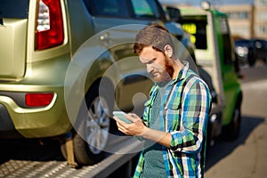 Man calling while tow truck picking up car