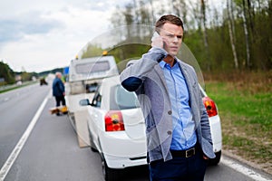 Man calling while tow truck picking up his broken car