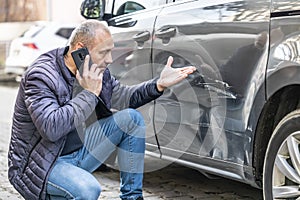 A man calls the insurance company because of the damaged door of his car because the culprit of the accident ran away from the photo