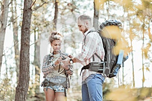 Man calming his appealing woman after being lost in forest with backpacks