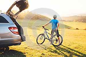 Man came by auto in mountain with his bicycle take it off and staying and enjoying landscape. Mountain biking concept image