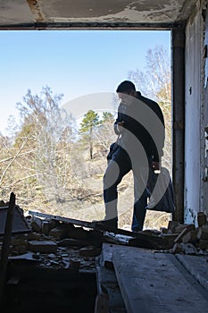 A man came to a ruined house and examines its remains, ruins, broken boards