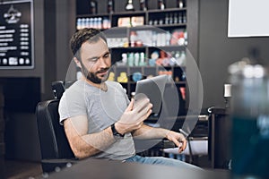 A man looks at the tablet in the barber`s chair in a man`s barbershop.