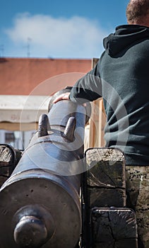 Man in camouflage holding old ball gunpowder canon