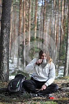 A man in a campaign drinks tea. A young traveler in the woods ca