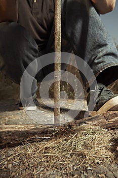 Man camping in nature making fire with wood stick friction by hands