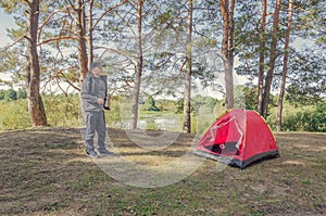 Man camping near the tent in the forest
