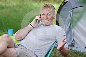 man camping teeth gritted while talking on telephone