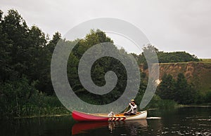 Man in canoe with his dog in a nature park on the river