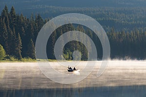 Man on a canoe. Mountains reflect over the calm waters of Sparks Lake at sunrise in the Cascades Range in Central Oregon, USA