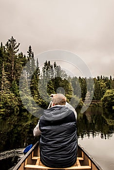 Man canoeing with Canoe on the lake of two rivers in the algonquin national park in Ontario Canada on cloudy day