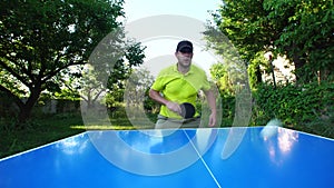 Man with cap plays table tennis outdoors