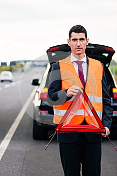 Man with car breakdown erecting warning triangle