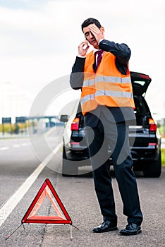 Man with car breakdown erecting warning triangle