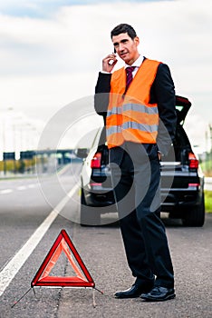 Man with car breakdown erecting warning triangle