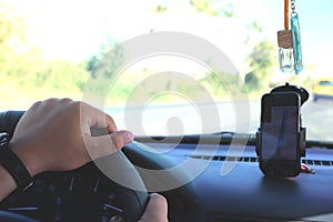 Man in the car and holding black mobile phone with map gps navigation, toned at sunset