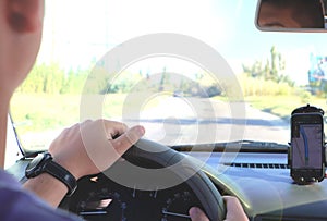 Man in the car and holding black mobile phone with map gps navigation, toned at sunset