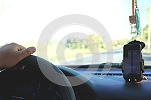 Man in the car and holding black mobile phone with map gps navigation, toned at sunset