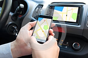 Man in car holding phone and multimedia system with map